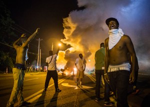 Demonstrators stand in the middle of West Florissant as they react to tear gas fired by police during ongoing protests in reaction to the shooting of Brown, in Ferguson